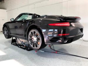 Black sports car on a lift undergoing paint correction at Elite Pro Car Care